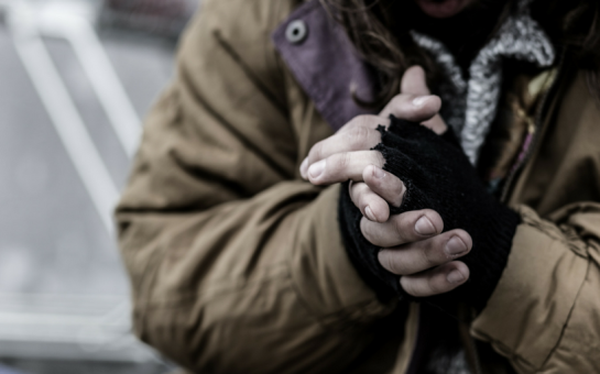 homeless person with fingerless gloves clasping their hands