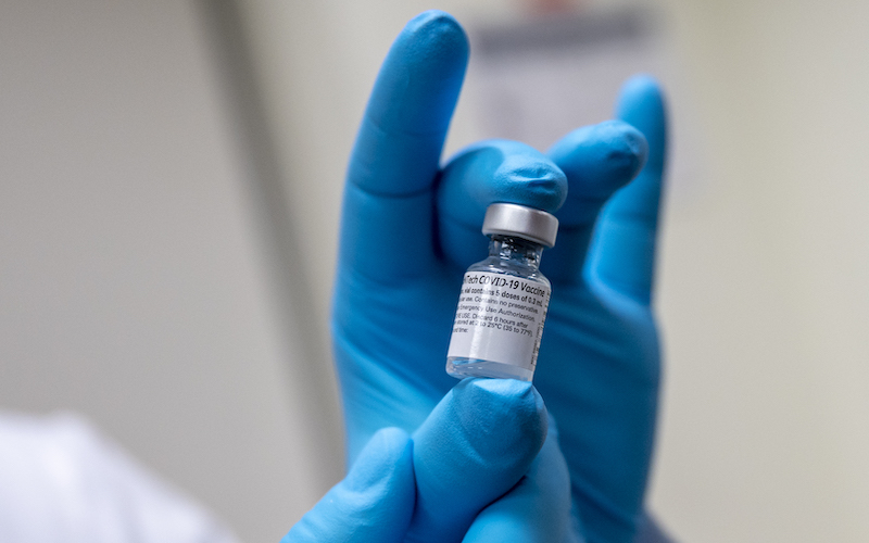 Army Spc. Angel Laureano holds a vial of the COVID-19 vaccine