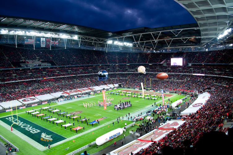 Wembley Stadium pitch covered with flags and people in pre match build up to NFL match