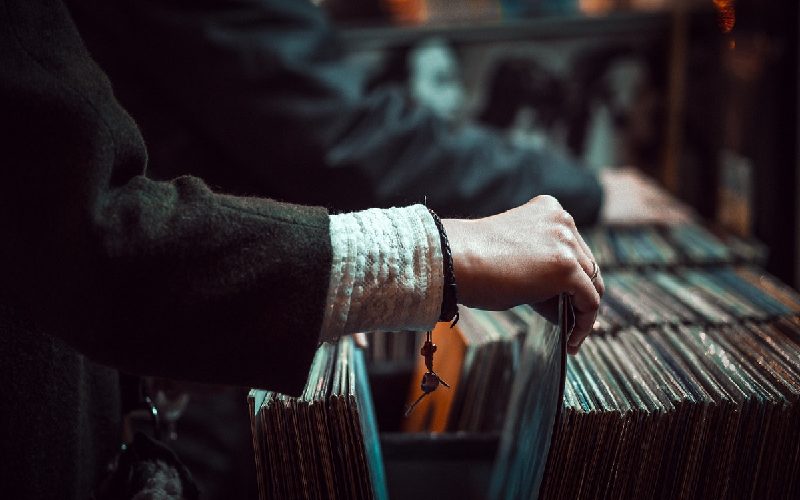 A hand browsing through a box of records