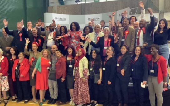 Islington's labour party members gather on stage together to celebrate with arms aloft in celebration