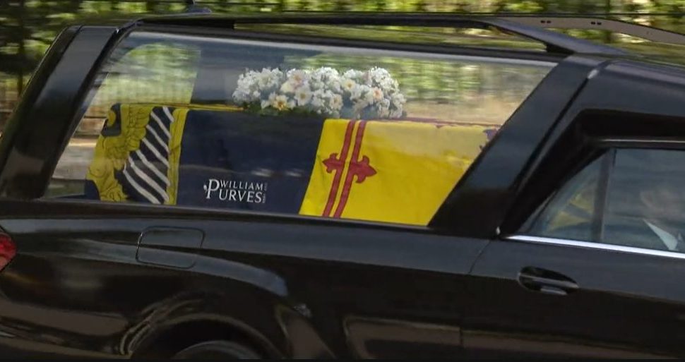 Queen Elizabeth's coffin wrapped in the Royal Standard of Scotland with a wreath of her favourite flowers from the Balmoral estate. Via iPlayer.