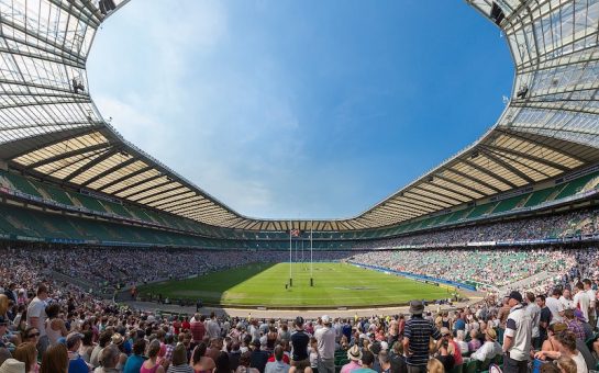 The interior of Twickenham stadium on a sunny day. Thousands of spectators are visible along with the green pitch. The Queen opened the East Stand at Twickenham Stadium in 1994.