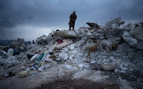 A man stands on the rubble of a destroyed building caused by the earthquake in north-west Syria