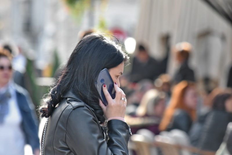 A woman is pictured holding a phone in a busy street.