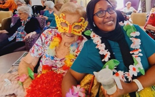 Two people sat smiling wearing carnival clothing