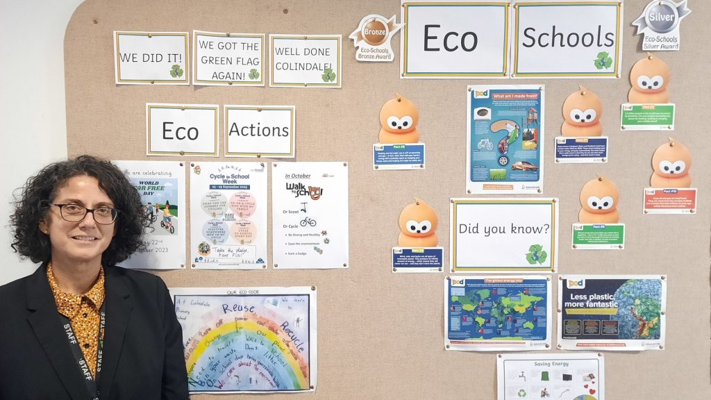 Colindale Primary School's Eco lead, Andrea Grigoriadou, standing in front of an eco display board at the school