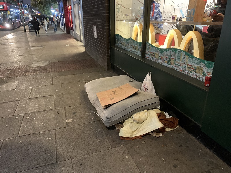 A picture of a mattress outside a fast food chain with a cardboard sign on top.