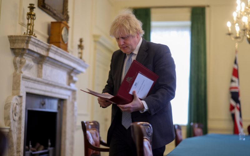 Boris Johnson reading from a red folder.
