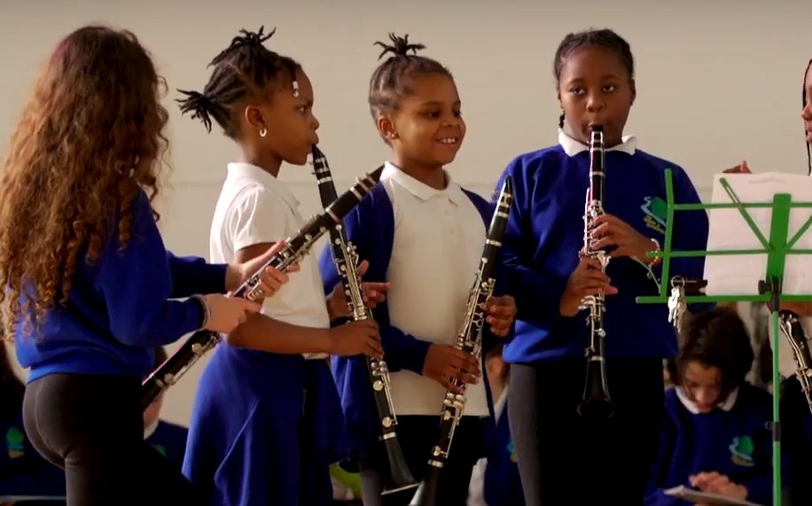 A group of three children playing the recorder