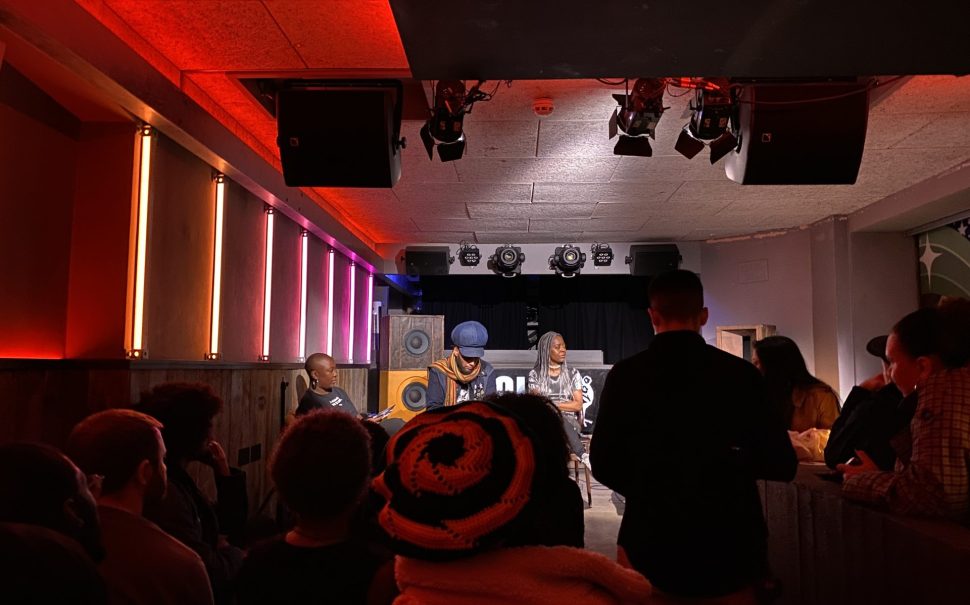 The event host and panellists sitting on a raised platform with audience in front.