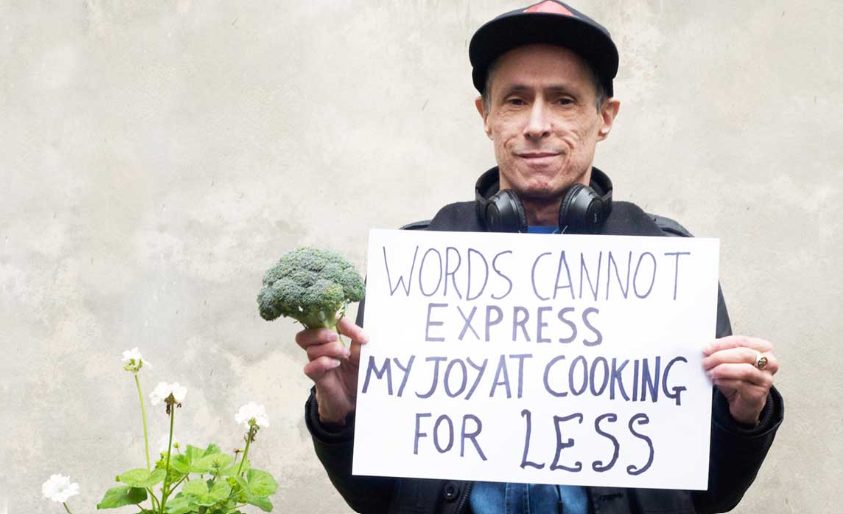 A man holding a sign saying 'Words cannot express my joy at cooking for less'