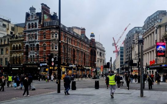 Tottenham Court Road, London, grey and gloomy on a Monday afternoon. There is a lot of traffic, including the hustle and bustle of Londoner's either going to work or seeking their lunch.