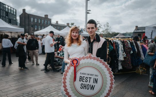 Two people in 50's style vintage clothing pose at the Classic Car Boot Sale at King's Cross.