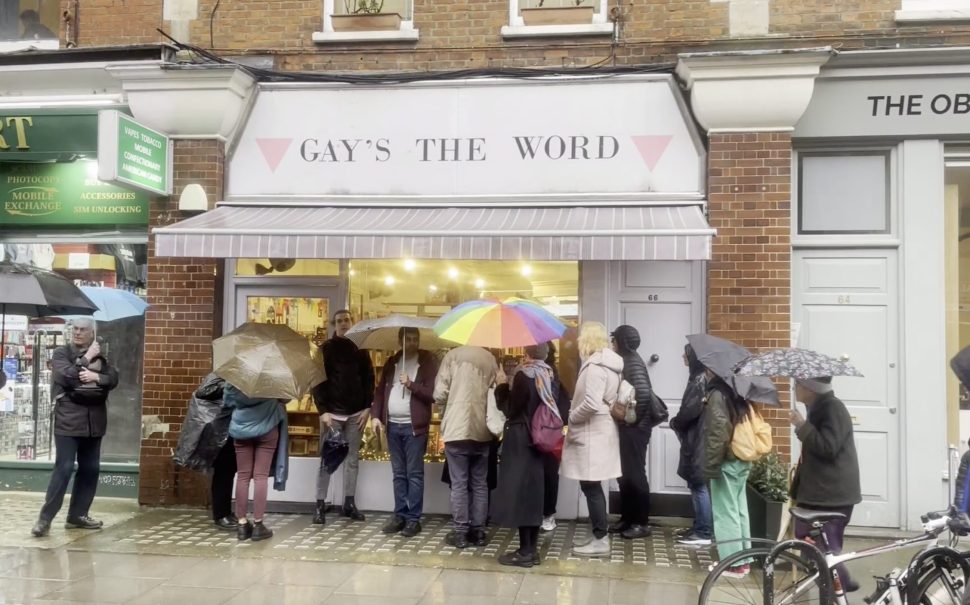 Image of Gay's The Word Bookshop, with someone holding a rainbow umbrella in front of it.