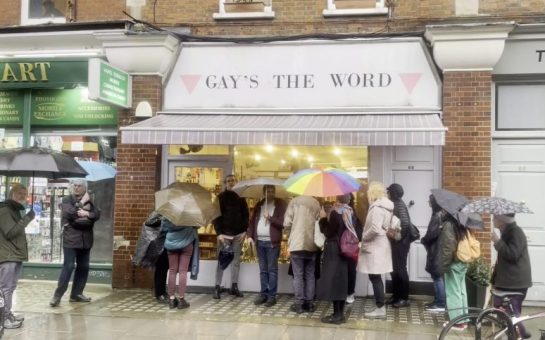 Image of Gay's The Word Bookshop, with someone holding a rainbow umbrella in front of it.