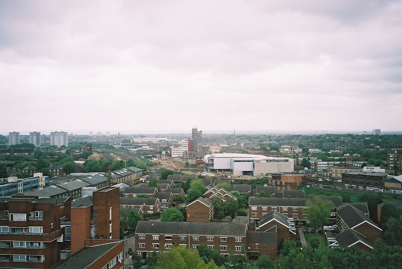 Image taken from Caledonian Park Clocktower, in Islington. Views over market estate housing estate and city suburb skyline further on, with some green space, and grey sky visible at the top.
