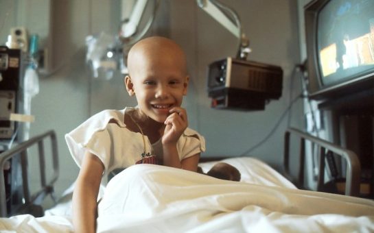Young girl with cancer in hospital bed receiving treatment