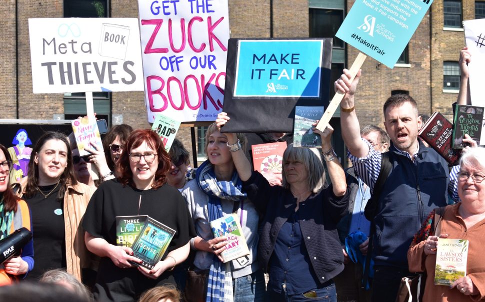 Authors hold up signs protesting the US company Meta's alleged use of copyrighted work without license