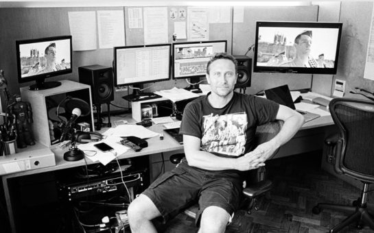A black and white picture of cancer patient Steve Ackroyd at a TV editing desk.