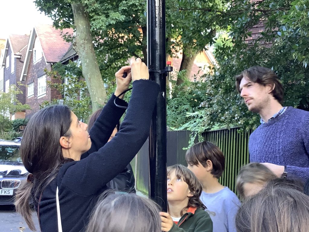 Francesca Agostini, Co-founder of Green School Runs pinning a monitor to a pole.