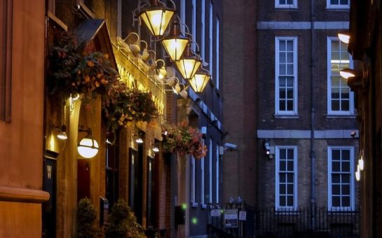 A London road at night time with street lamps.