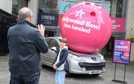 A giant bowling ball crushing a silver car outside of a shopping centre to launch Hollywood Bowl.