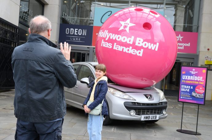 A giant bowling ball crushing a silver car outside of a shopping centre to launch Hollywood Bowl.