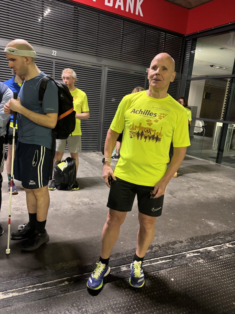 Chris Blackabee, president of Achilles UK, stood by Emirates Stadium in a fluorescent yellow shirt and black running shorts with trainers.