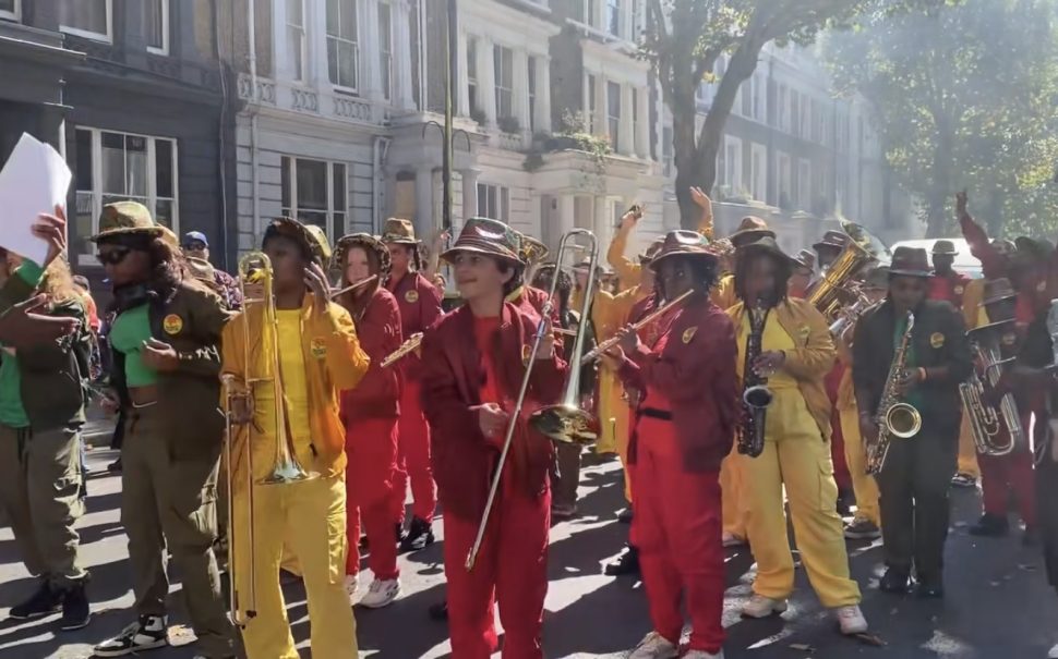 Attendees dancing down the street at Notting Hill Carnival, with bright yellow and red outfits.