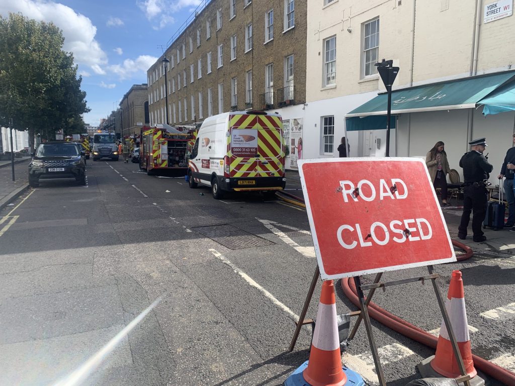 Road closed off by police with a red road closed sign