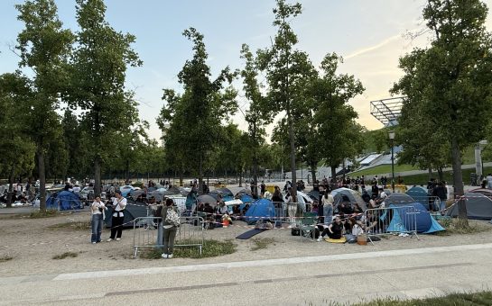 Numerous tents on the ground outside a concert venue.