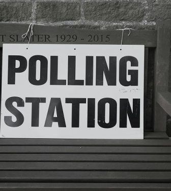 A picture of a sign saying "Polling Station" tied to a wooden bench. Photo by Steve Houghton-Burnett on Unsplash