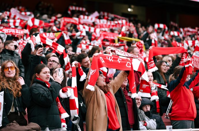 Arsenal fans in the Emirates Stadium stands holding their scarves up supporting their team (Credit: Suzy Lycett)