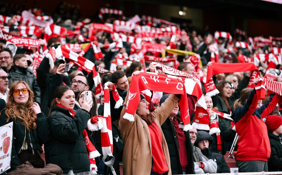 Arsenal fans in the Emirates Stadium stands holding their scarves up supporting their team (Credit: Suzy Lycett)
