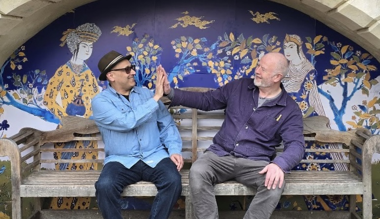 Mehrdad and a friend pose in front of a mural designed by him. 