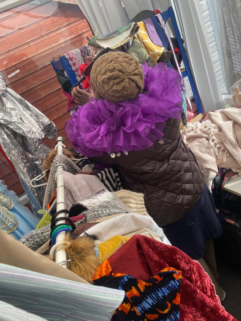 A woman organises clothes with a purple ruffle around her shoulders
