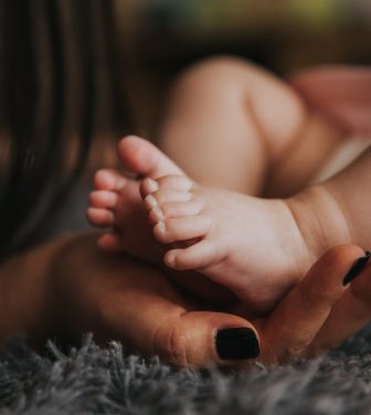 A child's foot being held by a mother's hand.
