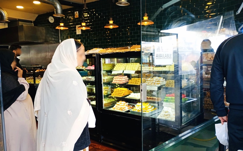 Woman browsing sweet shop counter Southall Broadway Ealing