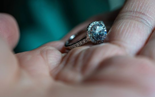 A person's hand holding a diamond ring.