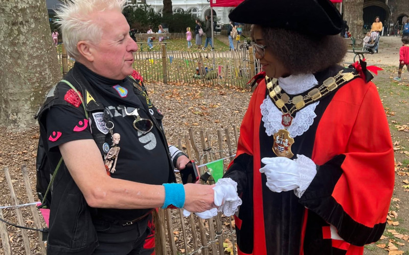Mayor of Islington Rosaline Ogunro and punk musician Spizz shake hands at a medieval fair.