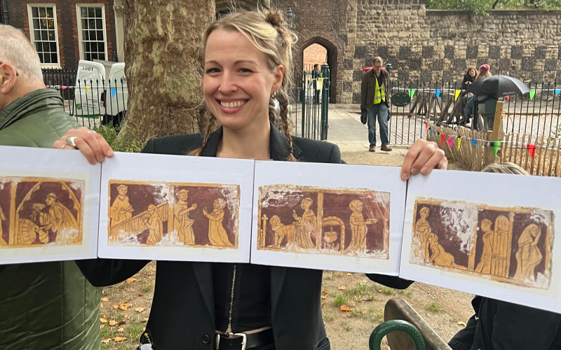 A woman holds up medieval drawings depicting sexual stories.